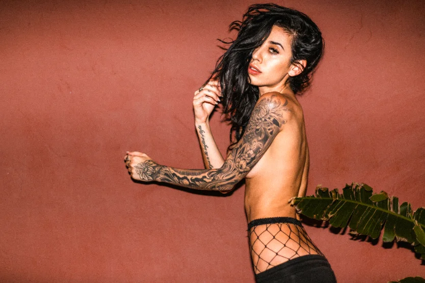Tattooed model in motion against a terracotta wall — Faces series by CRZYPNDA
