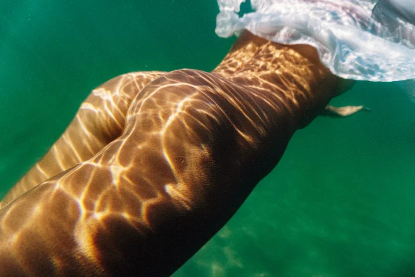 Swimmer in emerald green sea water with light patterns — CRZYPNDA underwater photography