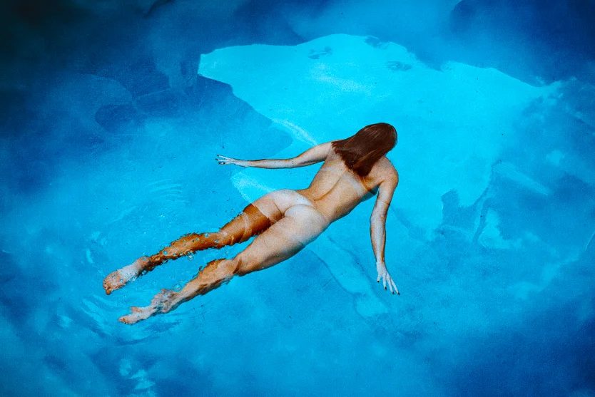 Swimmer gliding across a bright blue pool, shot from above — CRZYPNDA underwater photography